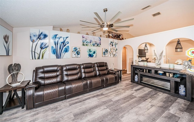 living room with a ceiling fan, wood finished floors, vaulted ceiling, and visible vents