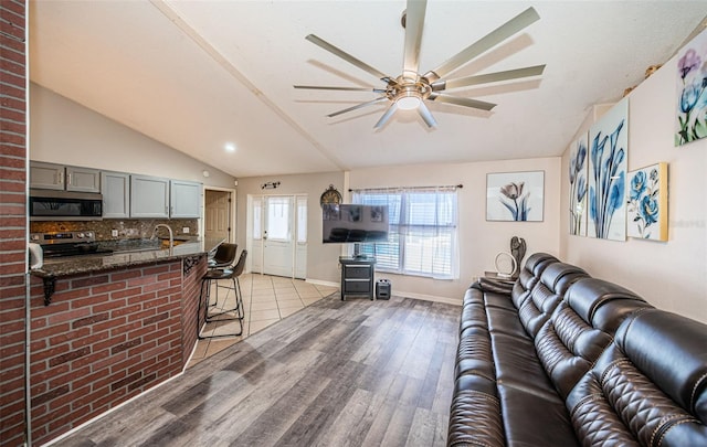living room featuring baseboards, vaulted ceiling, recessed lighting, light wood-style flooring, and a ceiling fan