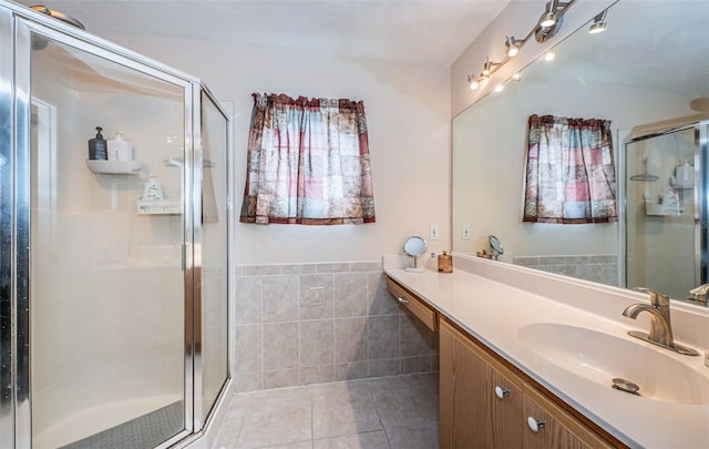bathroom featuring tile walls, tile patterned flooring, a stall shower, and vanity