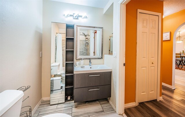 bathroom with toilet, a closet, wood finished floors, and baseboards