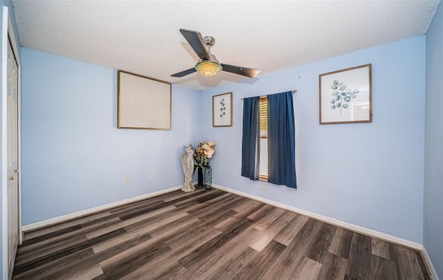 unfurnished room with dark wood-type flooring, a textured ceiling, baseboards, and a ceiling fan