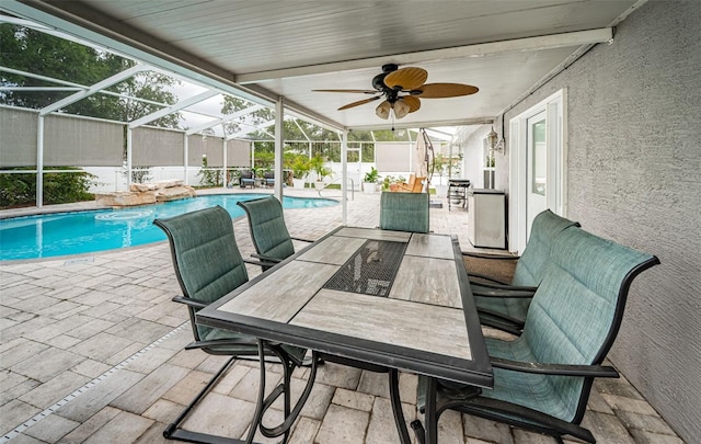 outdoor pool featuring outdoor dining space, a patio, glass enclosure, and ceiling fan