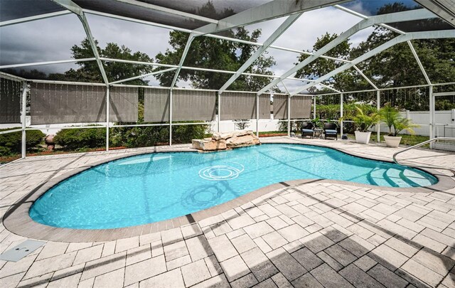 view of pool featuring a patio area, fence, a fenced in pool, and glass enclosure