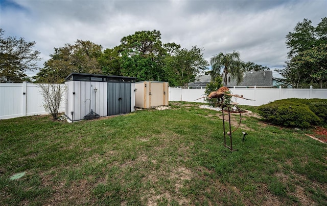 view of yard featuring a storage shed, a fenced backyard, a gate, and an outbuilding