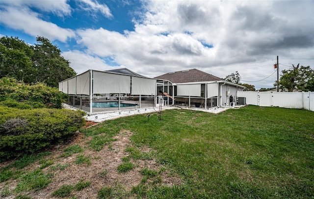 rear view of house featuring a fenced in pool, a patio area, a fenced backyard, a lanai, and a lawn