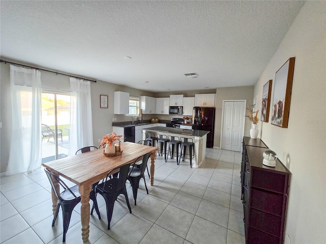 dining area featuring visible vents, light tile patterned flooring, and a textured ceiling