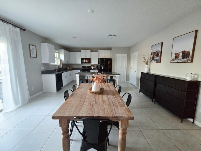 dining area featuring a textured ceiling, light tile patterned floors, baseboards, and visible vents
