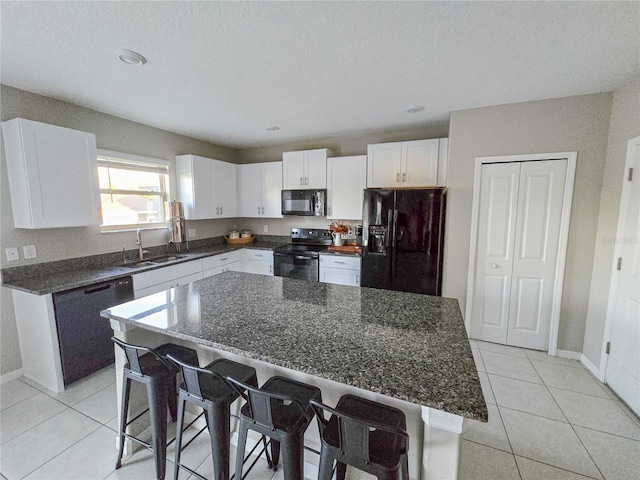 kitchen with light tile patterned floors, a sink, black appliances, and a kitchen bar