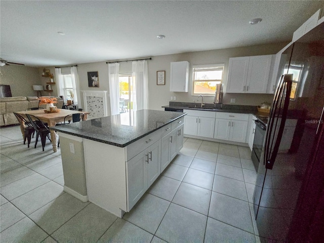 kitchen featuring a center island, light tile patterned floors, a sink, and white cabinetry