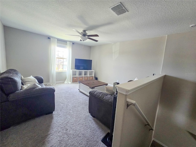 living area featuring a textured ceiling, a ceiling fan, visible vents, carpet flooring, and baseboards