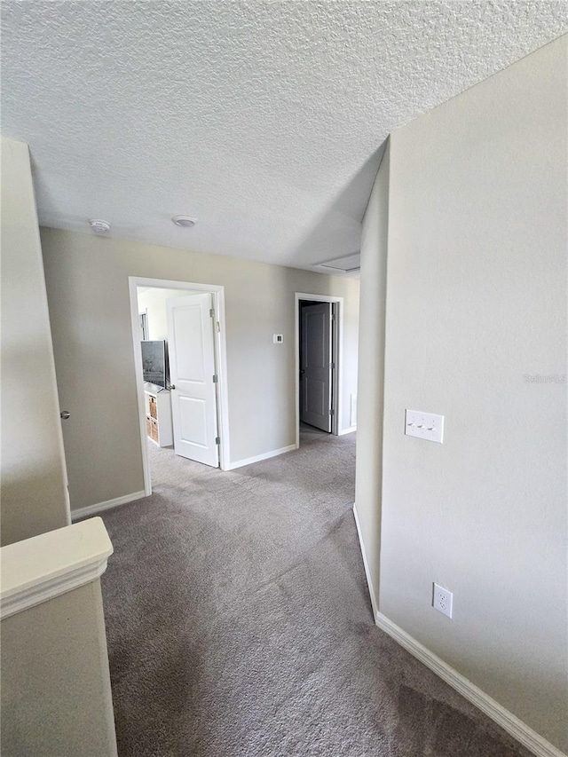 spare room with a textured ceiling, baseboards, and carpet floors