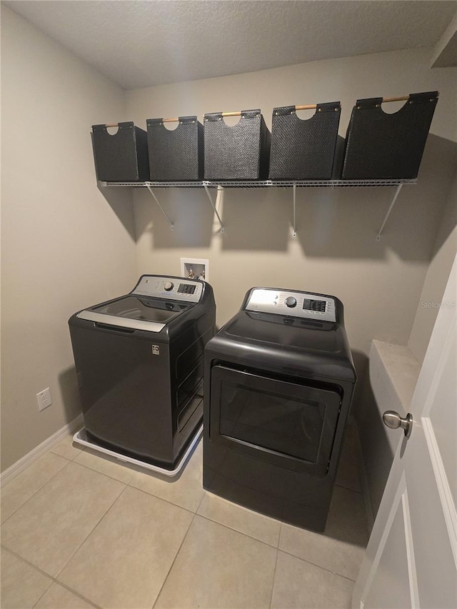 clothes washing area with independent washer and dryer, laundry area, baseboards, and light tile patterned flooring
