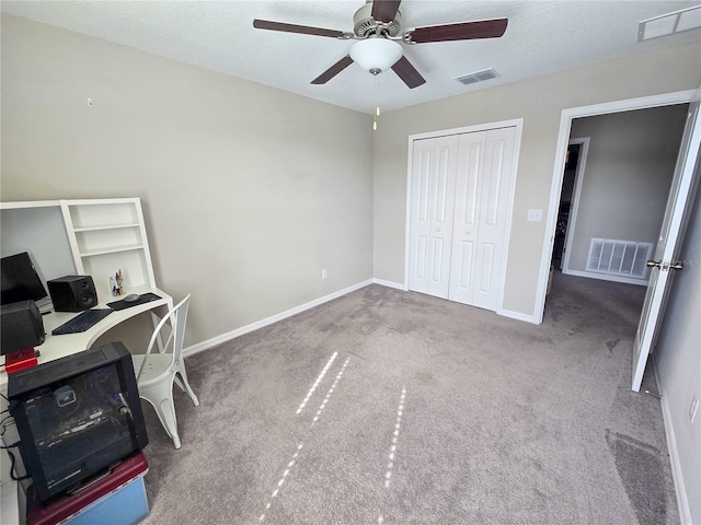 carpeted office space with visible vents, baseboards, and a ceiling fan