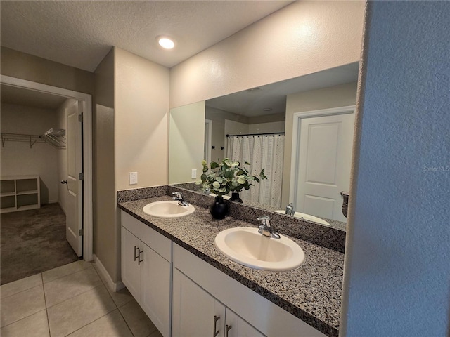 bathroom featuring a sink, a spacious closet, tile patterned floors, and double vanity