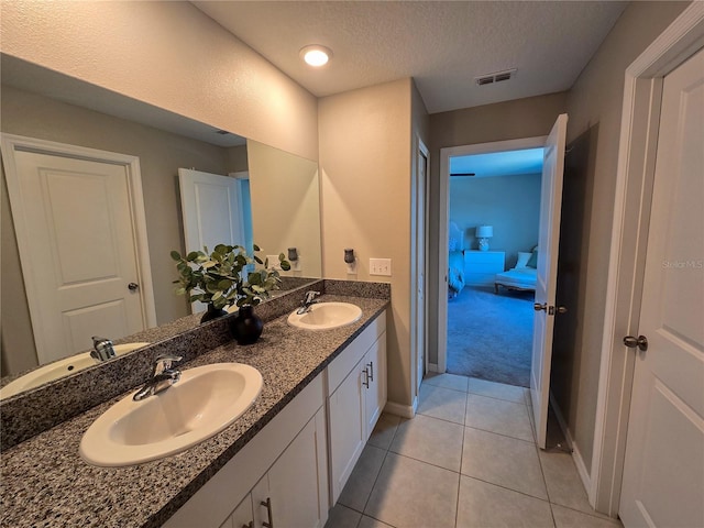 ensuite bathroom with baseboards, double vanity, a sink, and visible vents