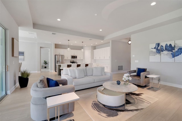 living room featuring light wood-style floors, baseboards, visible vents, and recessed lighting