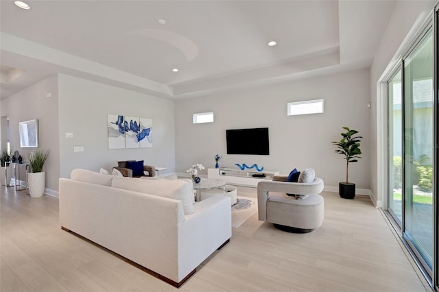 living room with a healthy amount of sunlight, recessed lighting, light wood-style flooring, and a raised ceiling