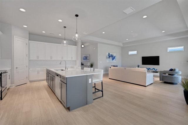 kitchen with light wood-type flooring, white cabinets, a sink, open floor plan, and range with electric cooktop
