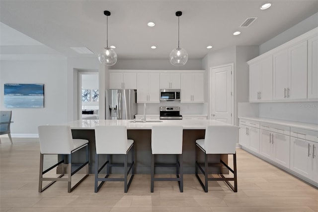 kitchen featuring recessed lighting, white cabinetry, a kitchen island with sink, stainless steel appliances, and a sink