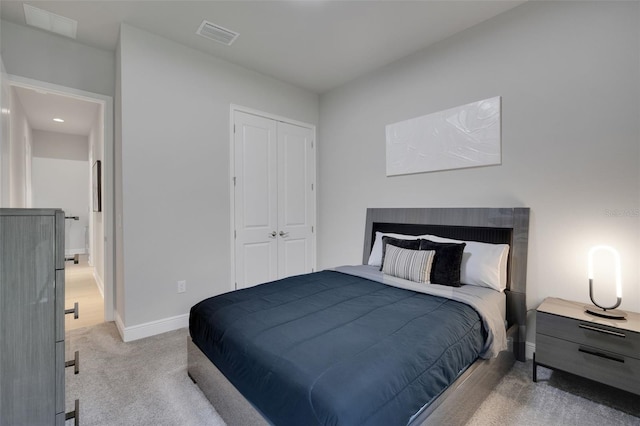 bedroom with a closet, visible vents, light colored carpet, and baseboards