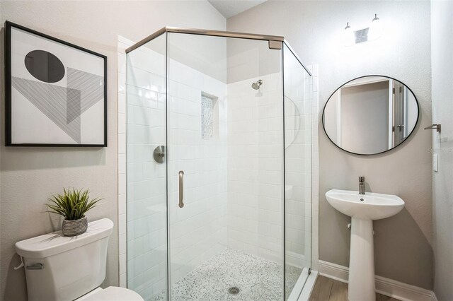 bathroom featuring toilet, a shower stall, wood finished floors, and baseboards