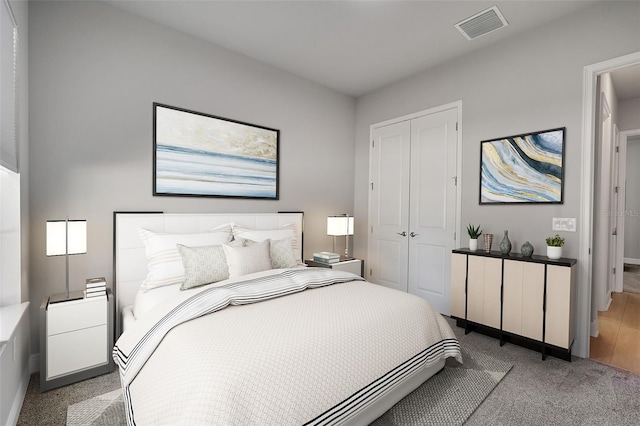 bedroom featuring visible vents, baseboards, a closet, and light colored carpet