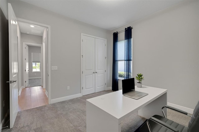 office space featuring light carpet and baseboards