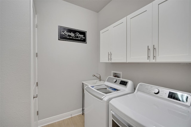 laundry room featuring baseboards, a sink, light wood-style floors, cabinet space, and washer and clothes dryer