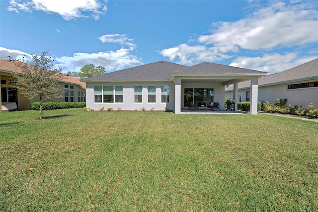 rear view of property with a patio area, a yard, and stucco siding
