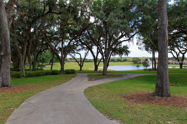view of community with golf course view, a yard, and a water view