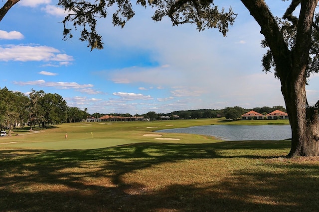 view of community with a water view, view of golf course, and a lawn