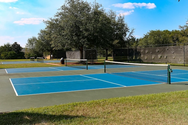 view of tennis court with community basketball court and fence