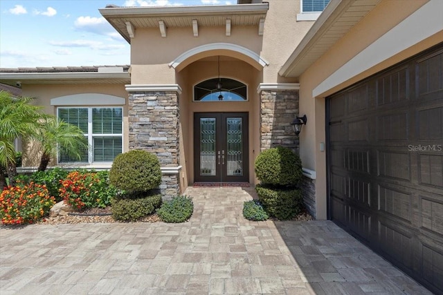 entrance to property featuring french doors, stucco siding, and stone siding