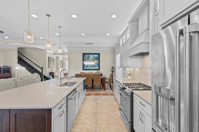 kitchen with high end appliances, custom range hood, a sink, and white cabinets
