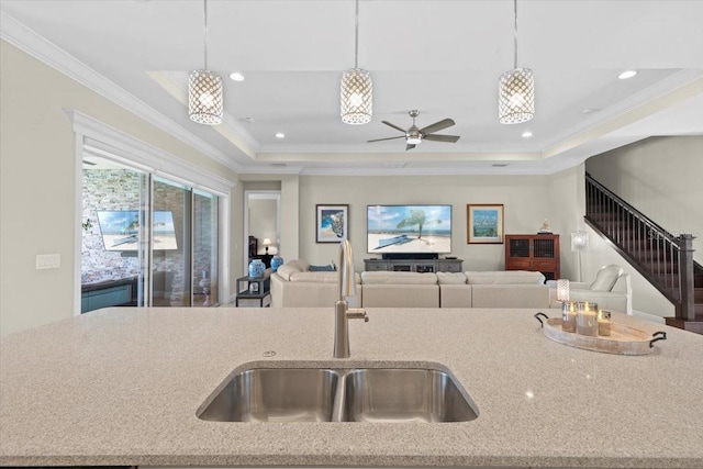 kitchen featuring a sink, open floor plan, hanging light fixtures, and light stone countertops