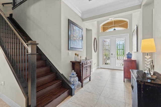 tiled entryway featuring french doors, ornamental molding, baseboards, and stairs