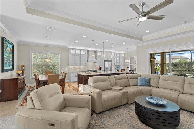 living area featuring a tray ceiling, ornamental molding, a ceiling fan, visible vents, and recessed lighting