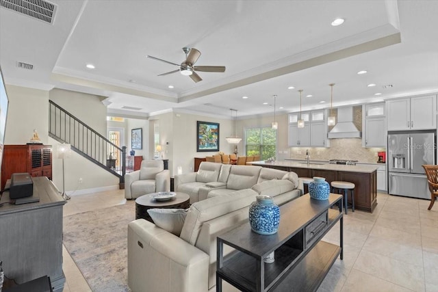 living area with visible vents, a ceiling fan, and a raised ceiling