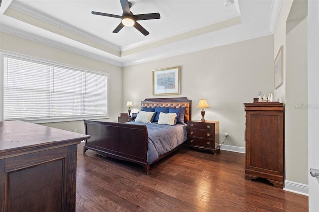 bedroom with crown molding, dark wood finished floors, a ceiling fan, a raised ceiling, and baseboards