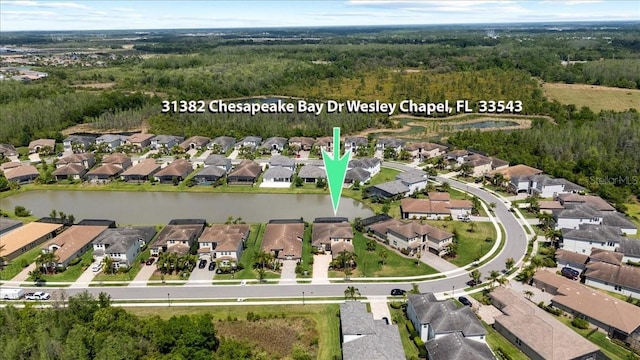 drone / aerial view featuring a water view, a residential view, and a view of trees