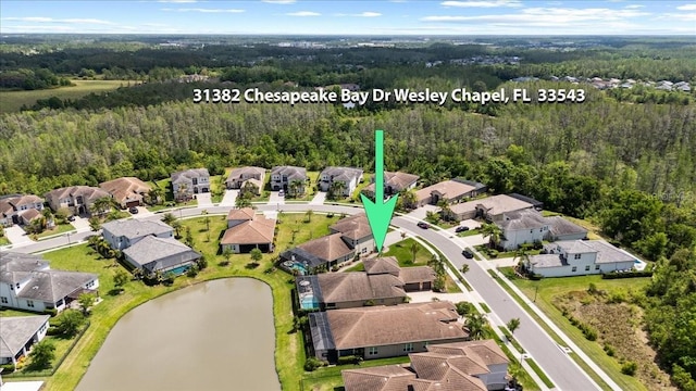 aerial view featuring a wooded view, a residential view, and a water view