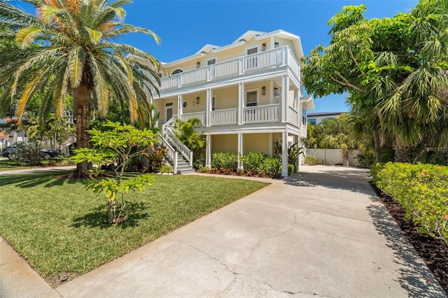 6113 Kipps Colony Dr W, Gulfport, FL 33707 - coastal home featuring a porch, concrete driveway, stairway, a front lawn, and a balcony