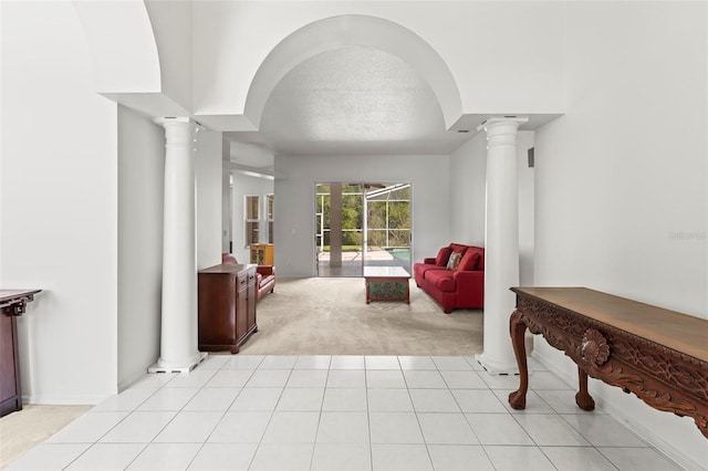 interior space with light tile patterned floors, ornate columns, light carpet, and a textured ceiling
