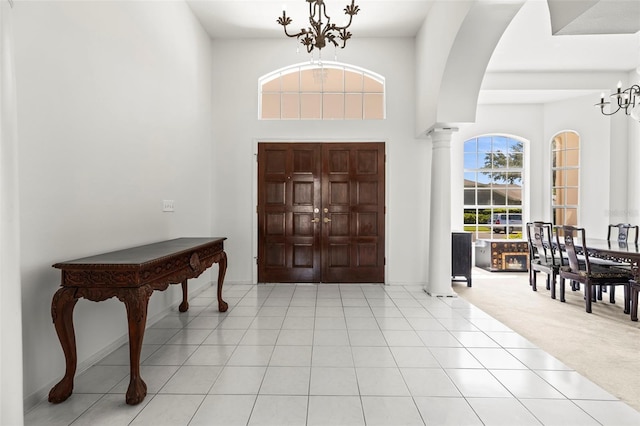 foyer entrance featuring a chandelier, arched walkways, a towering ceiling, and ornate columns