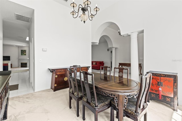 dining room with visible vents, arched walkways, a fireplace, ornate columns, and light colored carpet
