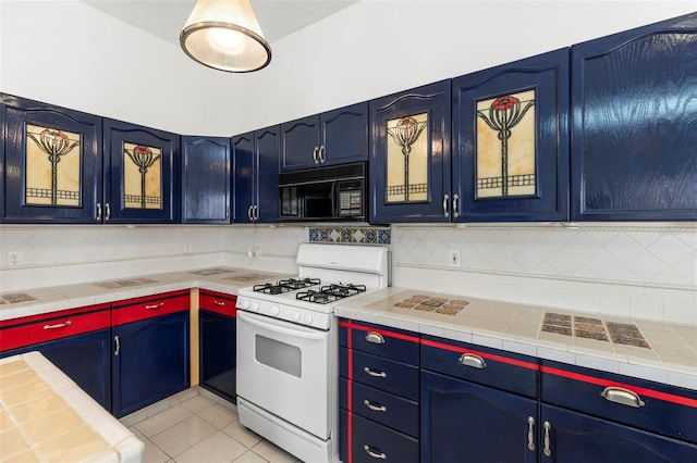kitchen featuring black microwave, decorative backsplash, light tile patterned floors, and gas range gas stove