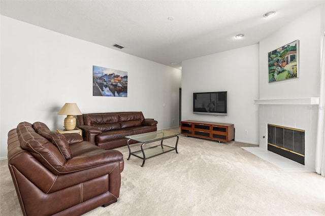 carpeted living area with a tiled fireplace, visible vents, and baseboards