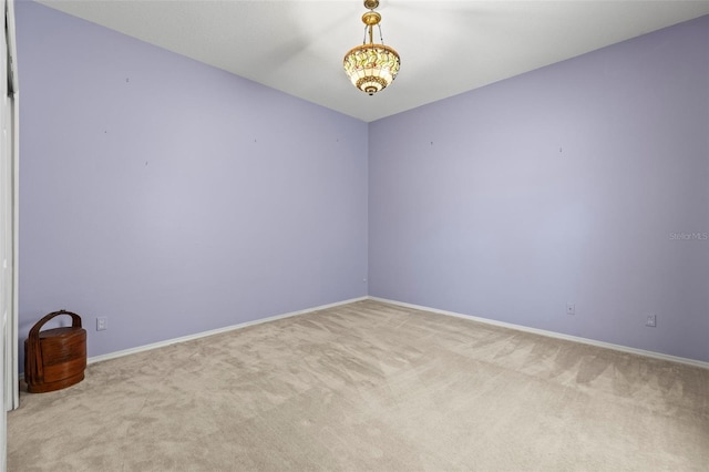 empty room featuring light colored carpet and baseboards