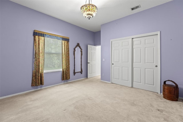 unfurnished bedroom featuring carpet, visible vents, a closet, and baseboards