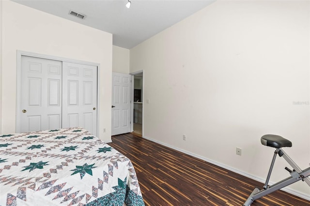 bedroom with a closet, dark wood-style flooring, baseboards, and visible vents